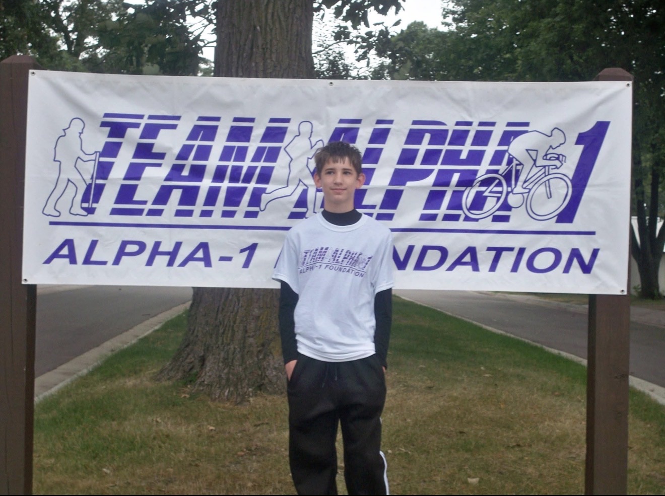 Young Josh standing in front of a Team Alpha-1 Foundation banner