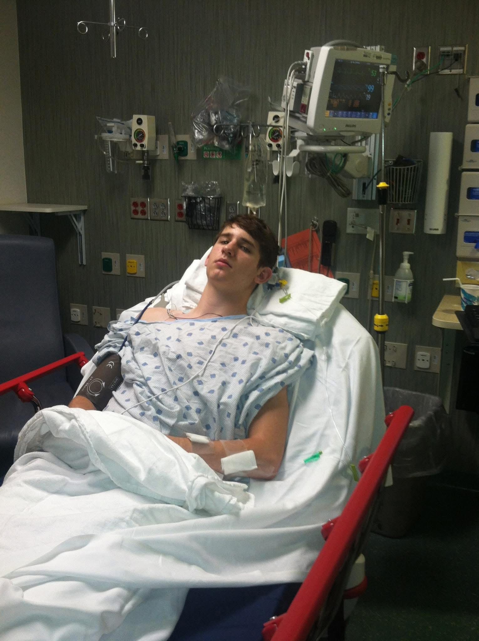 Josh as a teenager resting in a hospital bed while receiving medical care