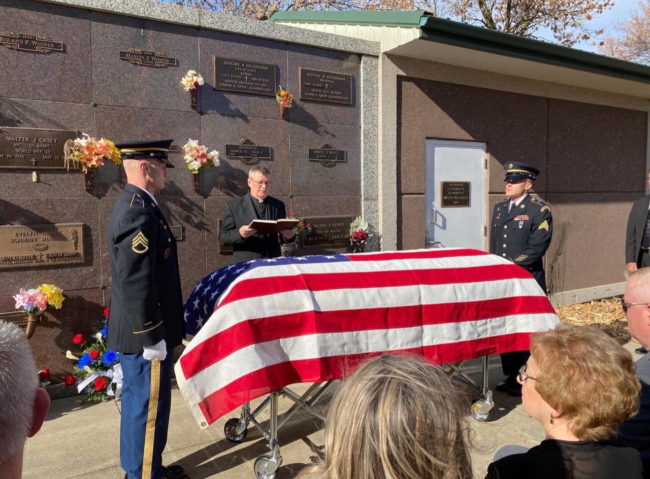 Military honor guard standing beside Tom Westcott’s flag-draped casket during his funeral service