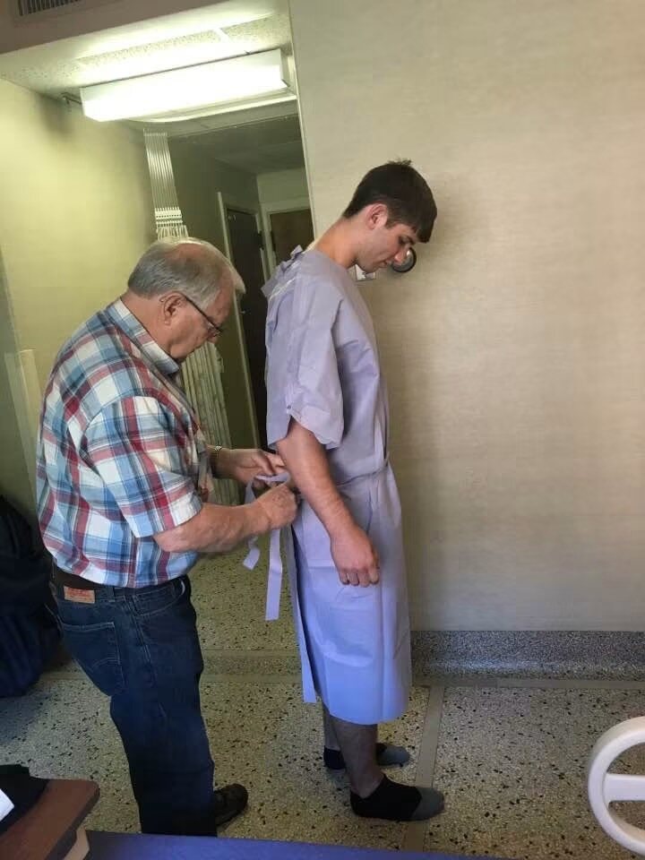 Thomas Emmett Westcott Jr. helping his grandson Josh Liljenquist with a hospital gown during one of Josh's medical visits.