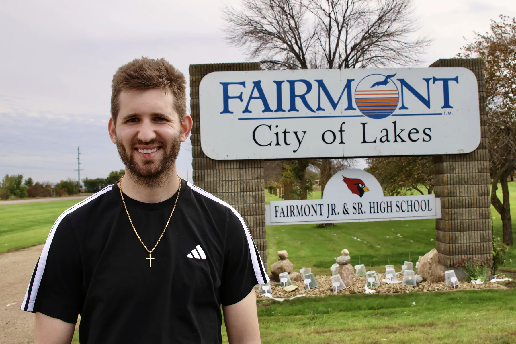 Josh Liljenquist standing beside the Fairmont City of Lakes and Fairmont Jr. & Sr. High School signs in Fairmont, Minnesota