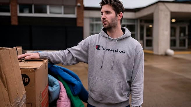 Josh Liljenquist standing beside boxes and winter clothing during a community outreach project