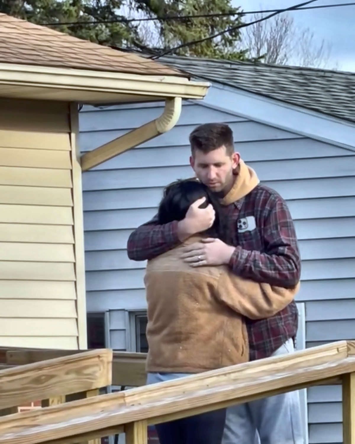 Josh Liljenquist embracing a woman on a residential accessibility ramp during an assistance story