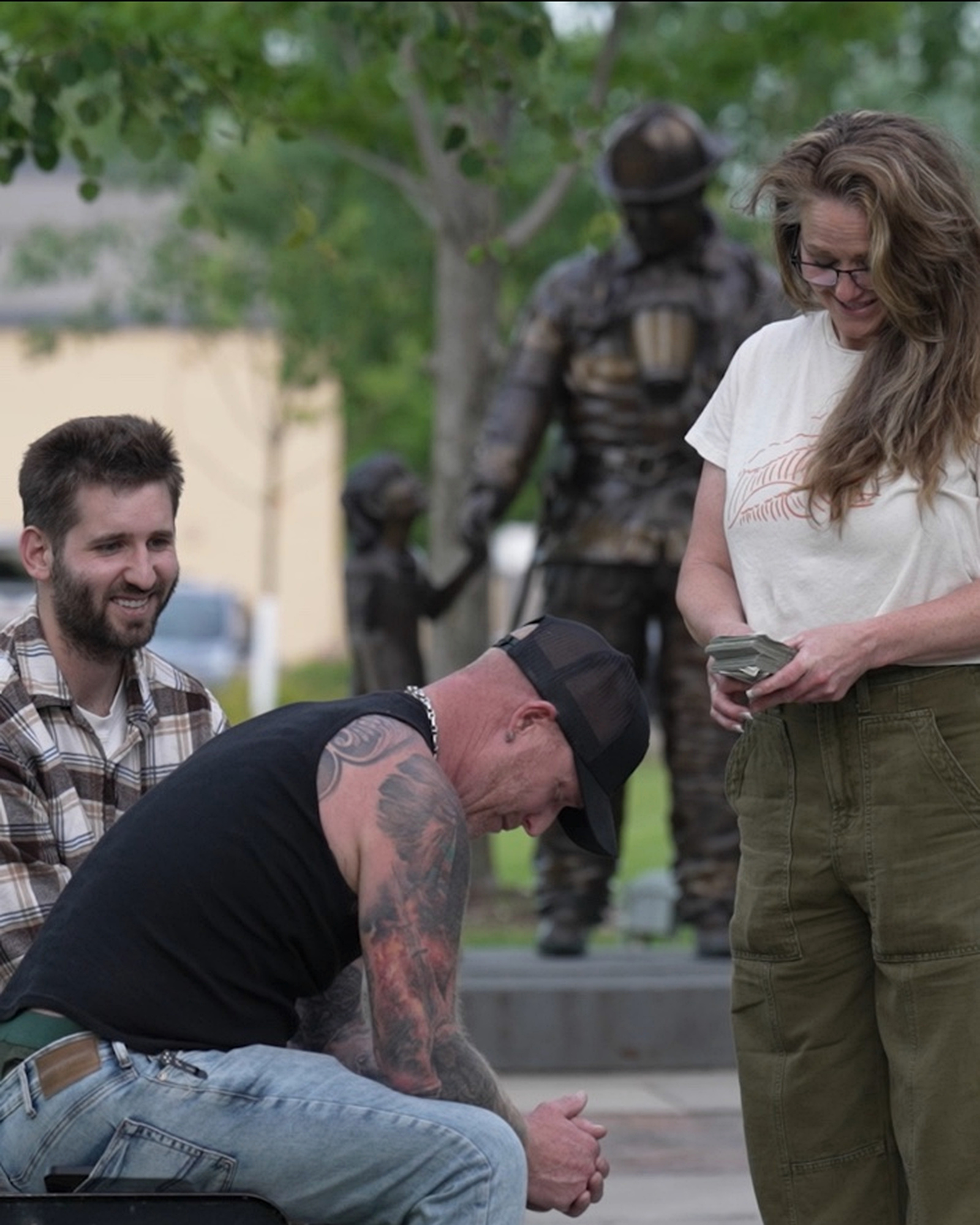 Josh Liljenquist seated beside an emotional recipient while a team member holds funds during a documented community-assistance moment