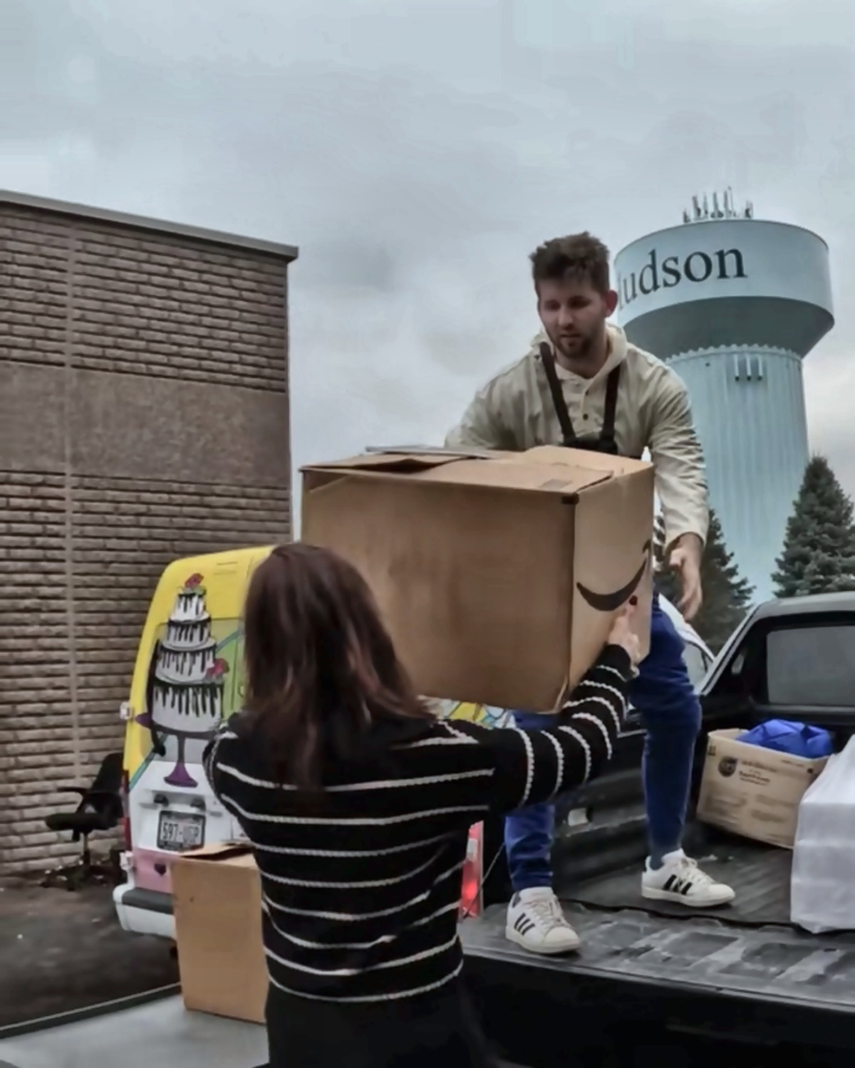 Josh Liljenquist handing a large supply box from a pickup truck to a woman during a community distribution
