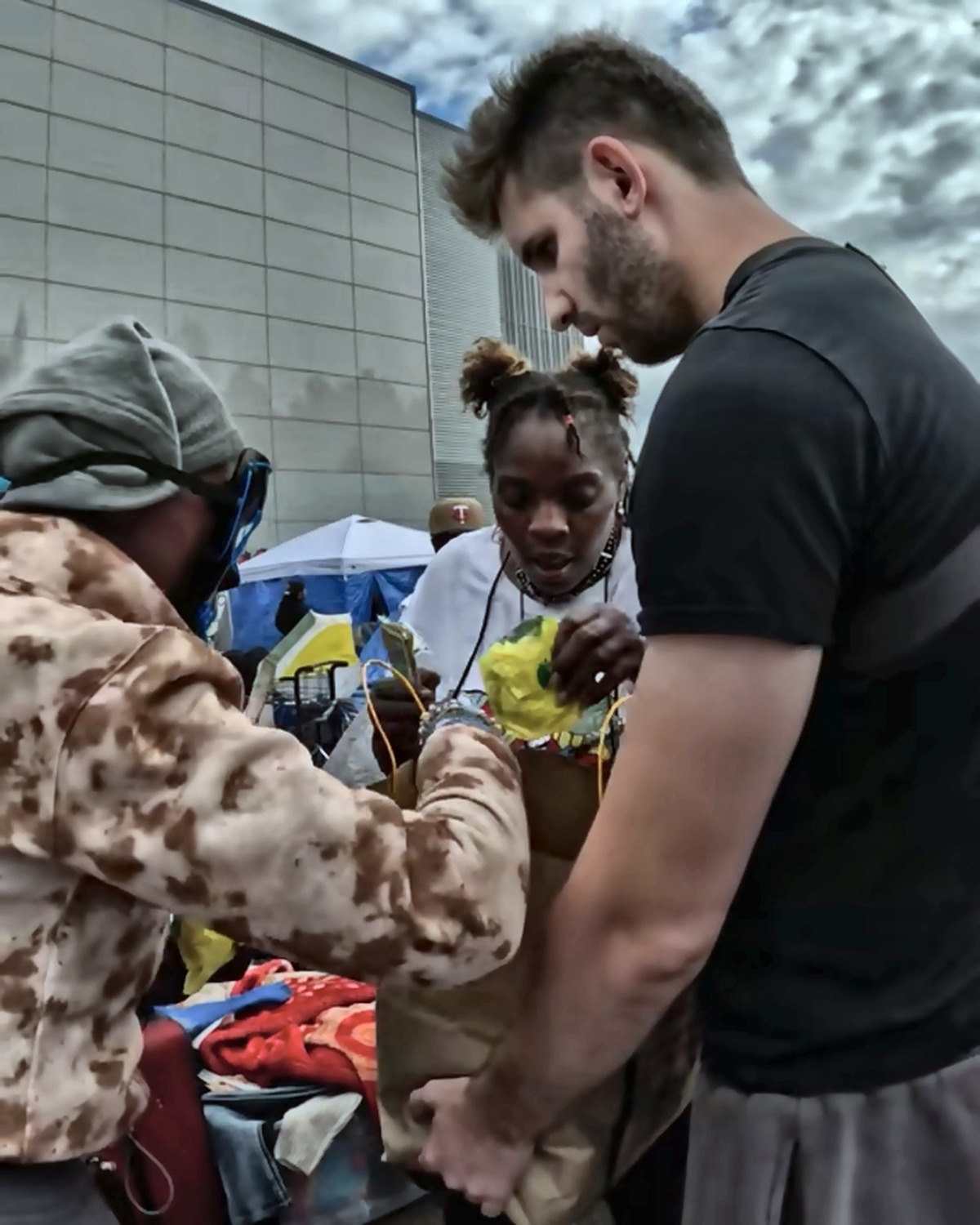 Josh Liljenquist holding a paper supply bag while community participants add items during an outreach project