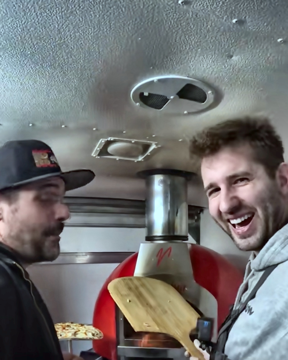 Josh Liljenquist smiling with a food-service collaborator beside a pizza oven