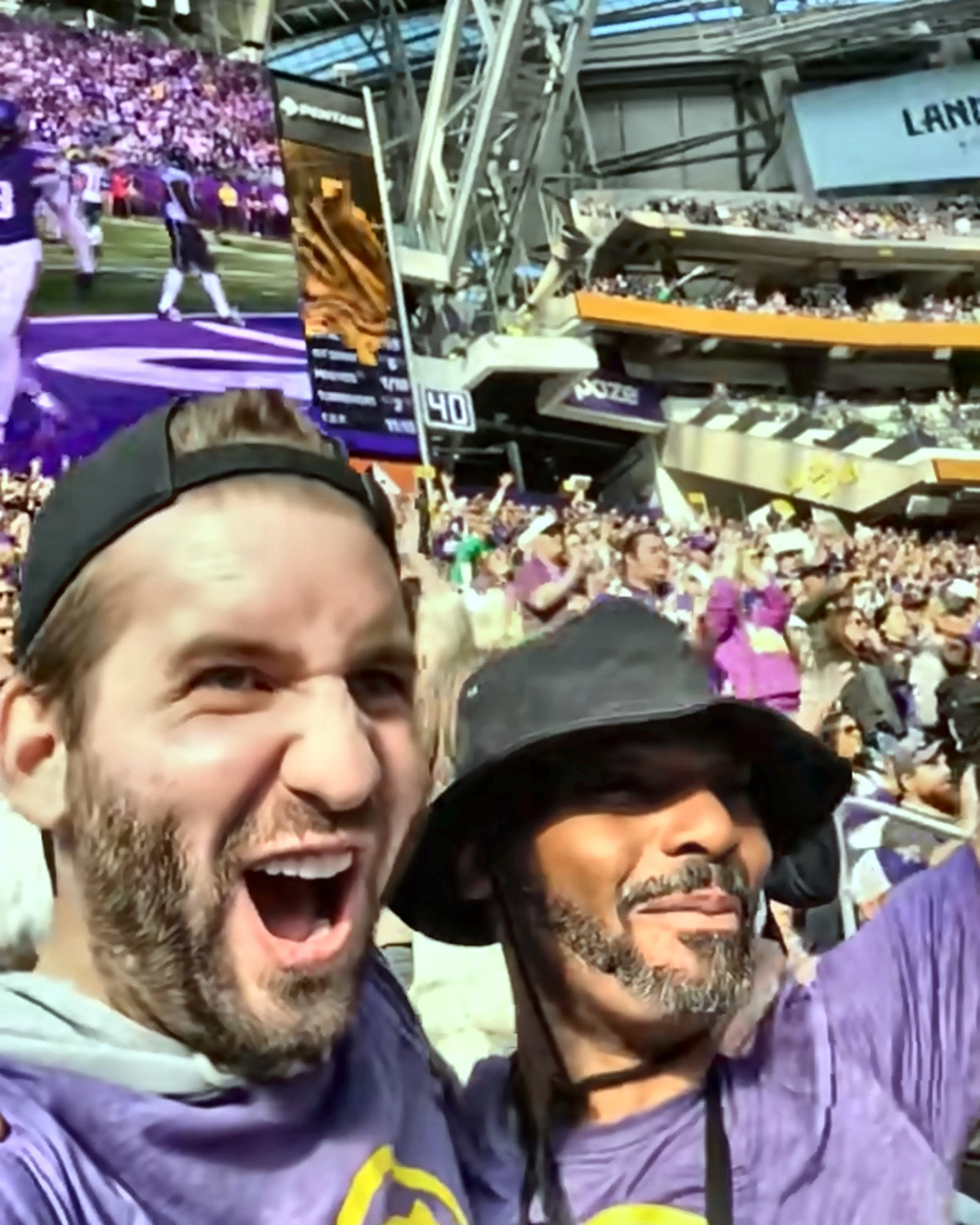 Josh Liljenquist celebrating with a community collaborator inside a crowded football stadium