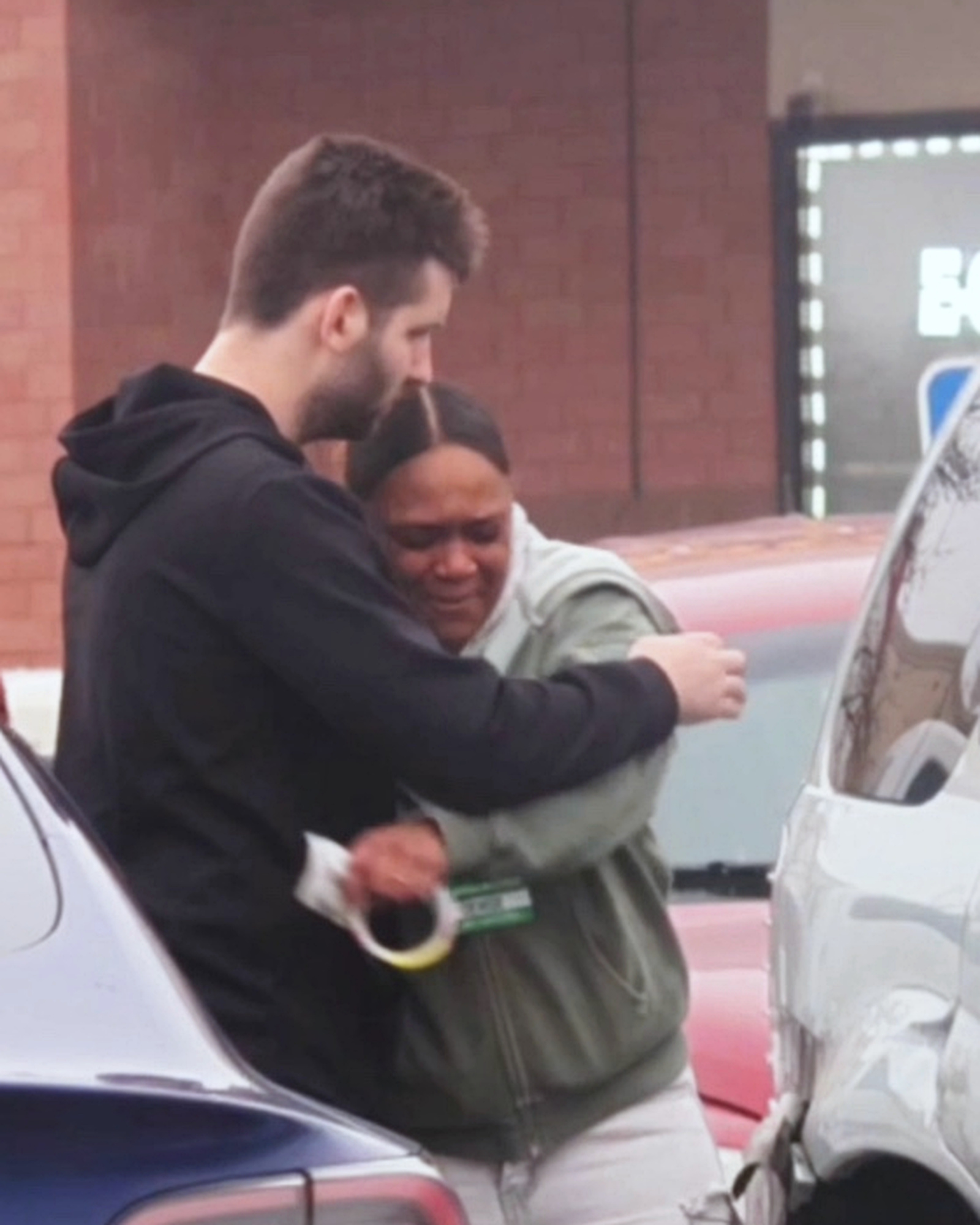 Josh Liljenquist comforting an emotional vehicle owner beside a visibly damaged vehicle after a repair-assistance offer