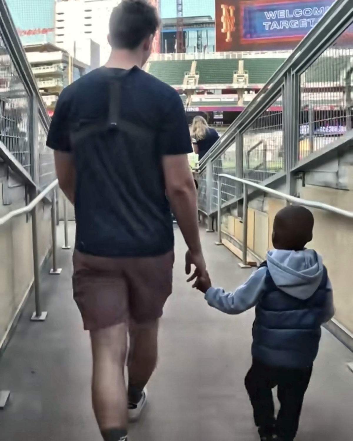 Josh Liljenquist walking hand in hand with a child toward a baseball field